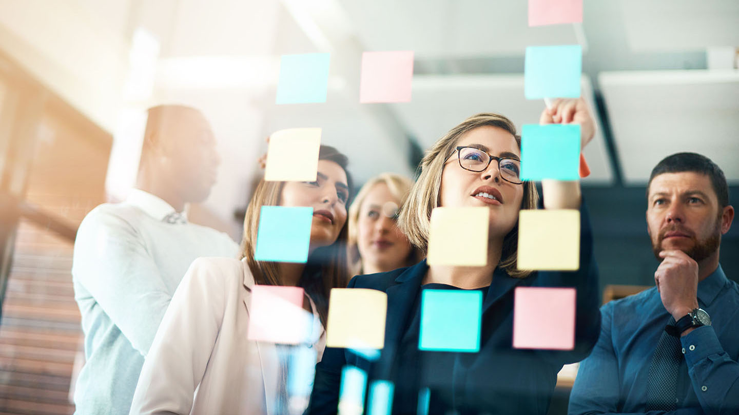Planning, innovation and vision business meeting in a modern office, working on a business marketing strategy. Group, team or staff discussing with sticky notes a schedule for future project