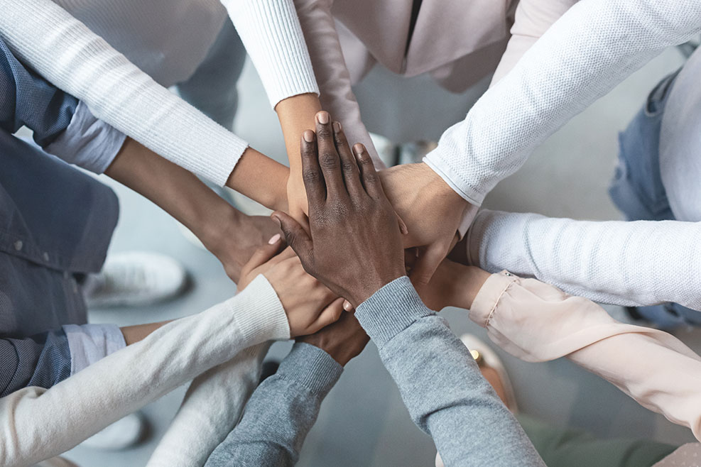 PInternational business team putting hands together in cooperation
