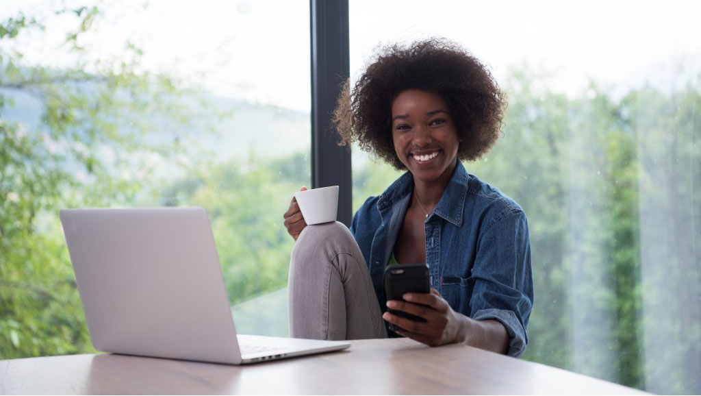 Woman smiling, and holding a cup of coffee